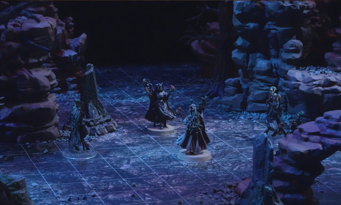 A battlemap with Fearne facing off against Dark Fearne and surrounded by three clones of Dark Fearne. Natural rocky towers and leafless trees stand around them.