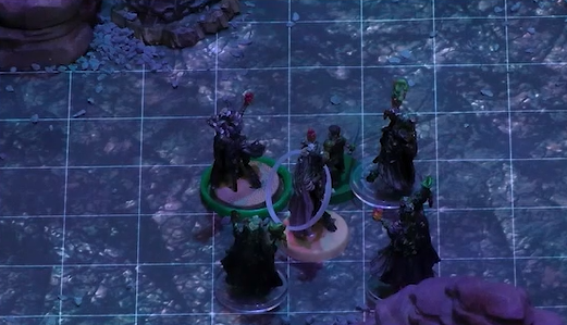 A battlemap with Fearne and Orym tightly surrounded by Dark Fearne and three clones of Dark Fearne. Status condition rings are around Fearne and Dark Fearne.