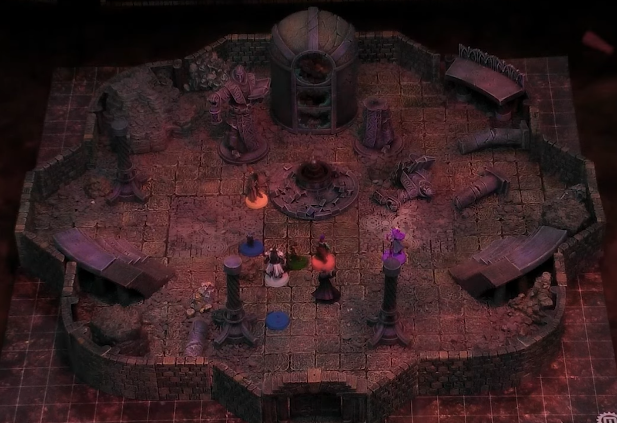 A battlemap of a circular indoor chamber with the party standing loosly in the middle of it. In the center of the chamber is a circular platform on which sits an orb. Behind it is a tall hollow structure with broken windows. Two large statues stand between the platform and structure, the right one’s body broken at the waist and lying on the ground. Ruined pillars and bleachers fill the rest of the space.