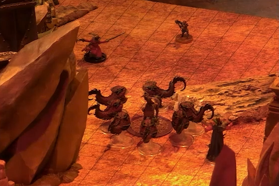 A battlemap focusing on Sam as a centaur surrounded by slithers, small scaley toothed creatures with round bodies, long tails, and no limbs. A large rock outcropping looms over them.