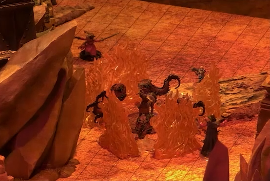 A battlemap focusing on Sam as a centaur surrounded by slithers, small scaley toothed creatures with round bodies, long tails, and no limbs. Surrounding the group is a wall of fire. A large rock outcropping looms over them.