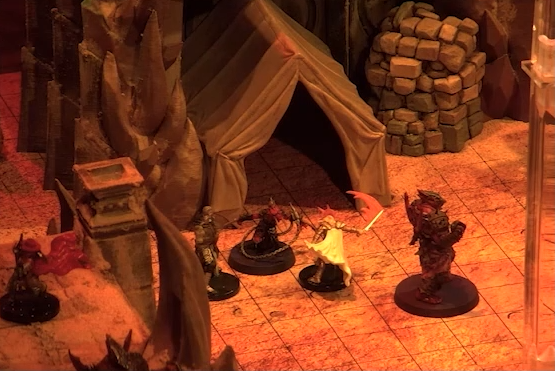 A battlemap focusing on Reilorans and others in combat in front of an open rectangular tent. Around the tent is sand and stone walls.