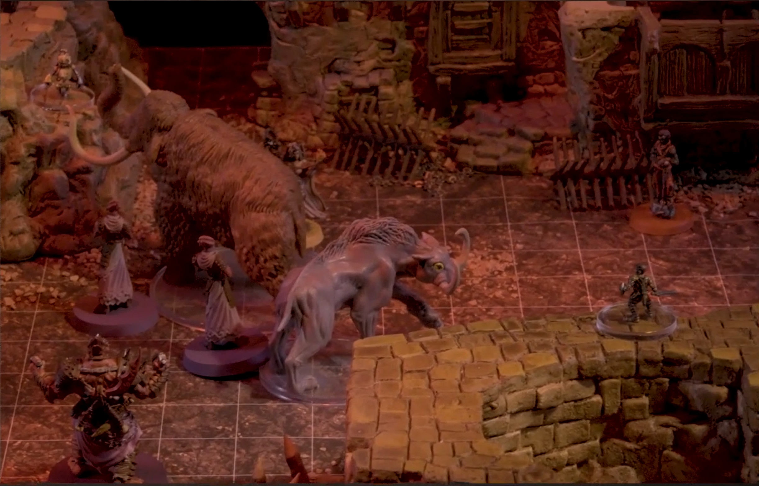 A street between a few buildings. Three Reilorans are accompanied by a wooly-mammoth-like creature and a smaller tusked tiger-like creature. Fearne is behind the wooly mammoth and FCG is on some rocks in front of it.