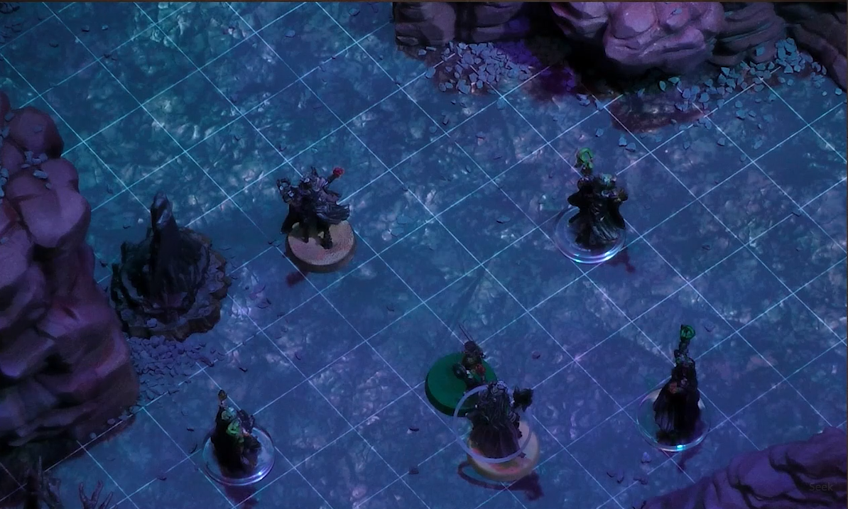 A battlemap with Fearne facing off against Dark Fearne and three clones of Dark Fearne. Orym stands in front of Fearne, who has a status condition ring around her token. Natural rocky towers stand around them.