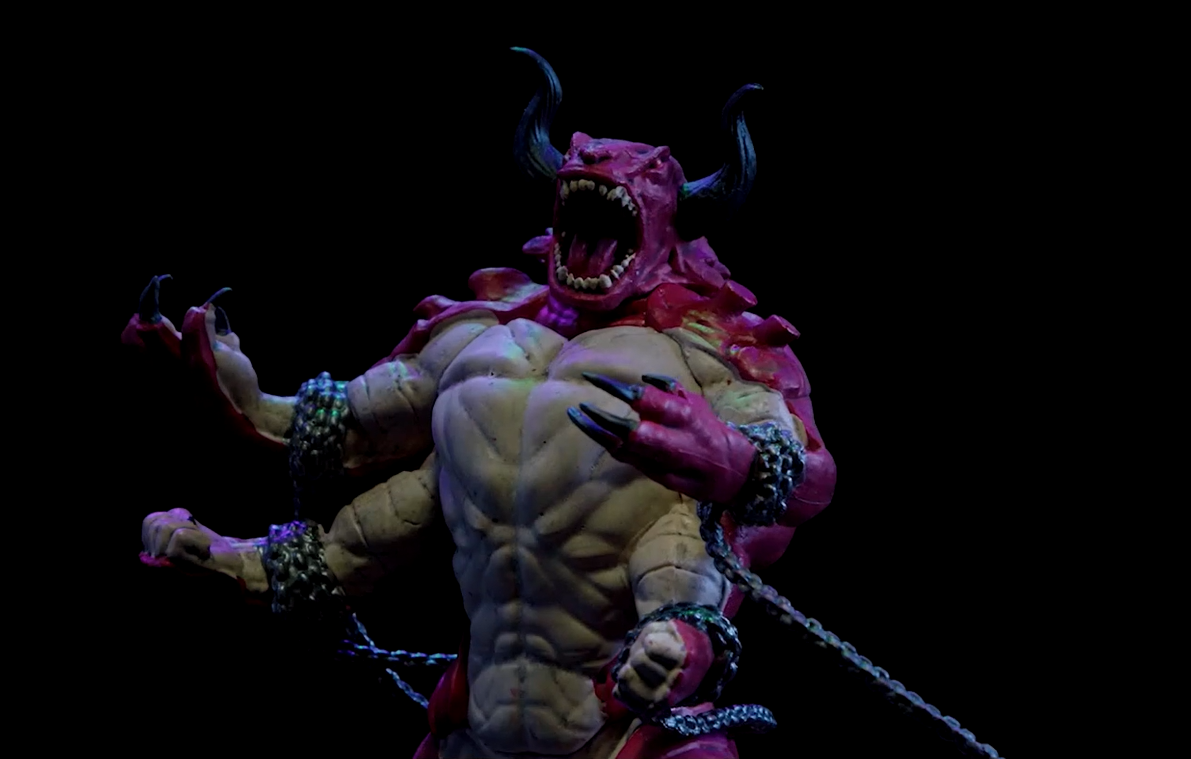 A close-up of a Dominox minature. A huge red beast with four muscular arms bound with chains, two black horns, and a roaring tooth-filled mouth.