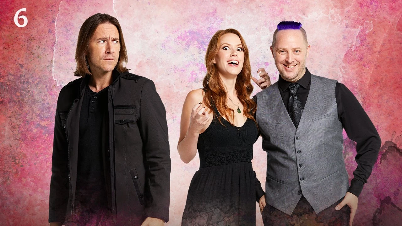 Thumbnail for episode 6. Marisha and Taliesin pose together with Matt slightly off to the left. Marisha and Talisin are grinning, Marisha giving a frightening smile. Matt looks towards them with a scared expression. They are dressed in black and gray and stand against a colorful backdrop with splashes of reds, purples, and blacks over white.