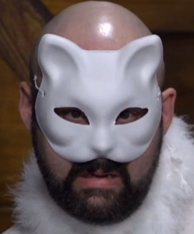 A person in a white cat mask covering the upper half of their face. They have a bald head, a black beard, and are grimacing menacingly.