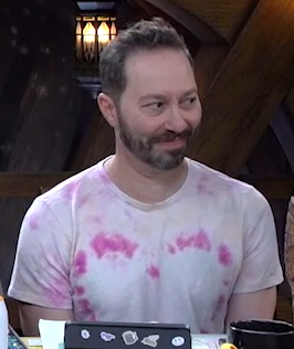 Sam wearing a pale pink and purple tie-dye shirt. A darker shade of pink forms the shape of a heart across the chest.