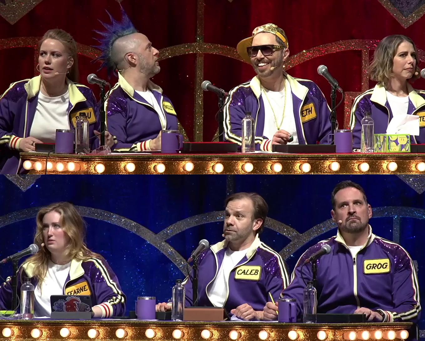 Marisha, Taliesin, Sam, Laura, Ashley, Liam, and Travis sitting at tables on a stage. They all look around in alarm and confusion. All wear purple track suits.